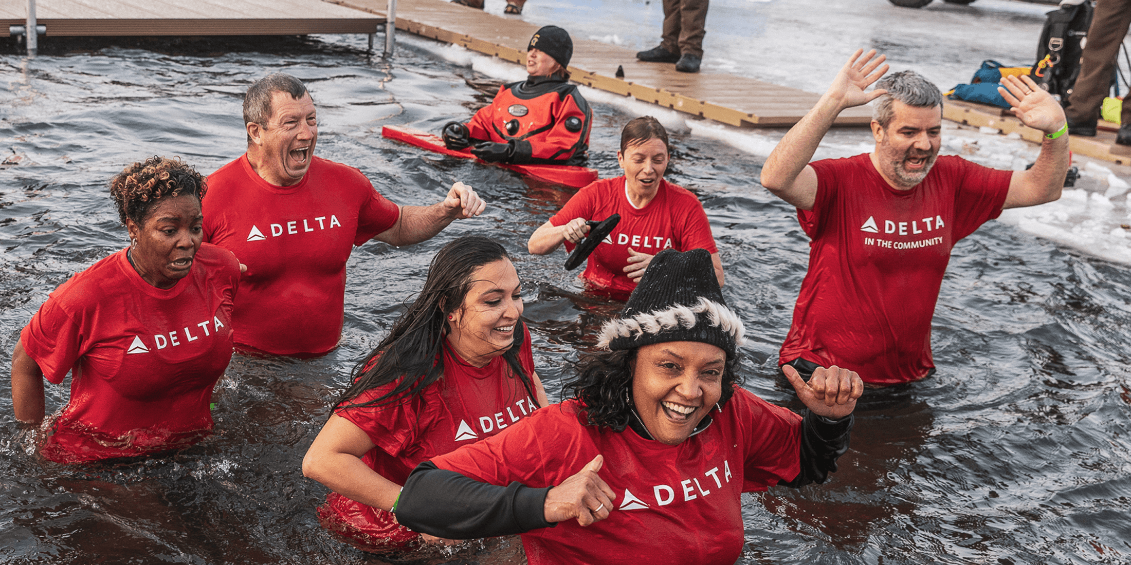 A group of smiling Delta Plungers wearing red shirts exit the Plunge hole
